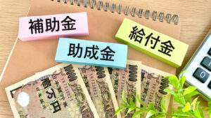 補助金・助成金・給付金 の文字がかいてある、下には一万円札も写っている